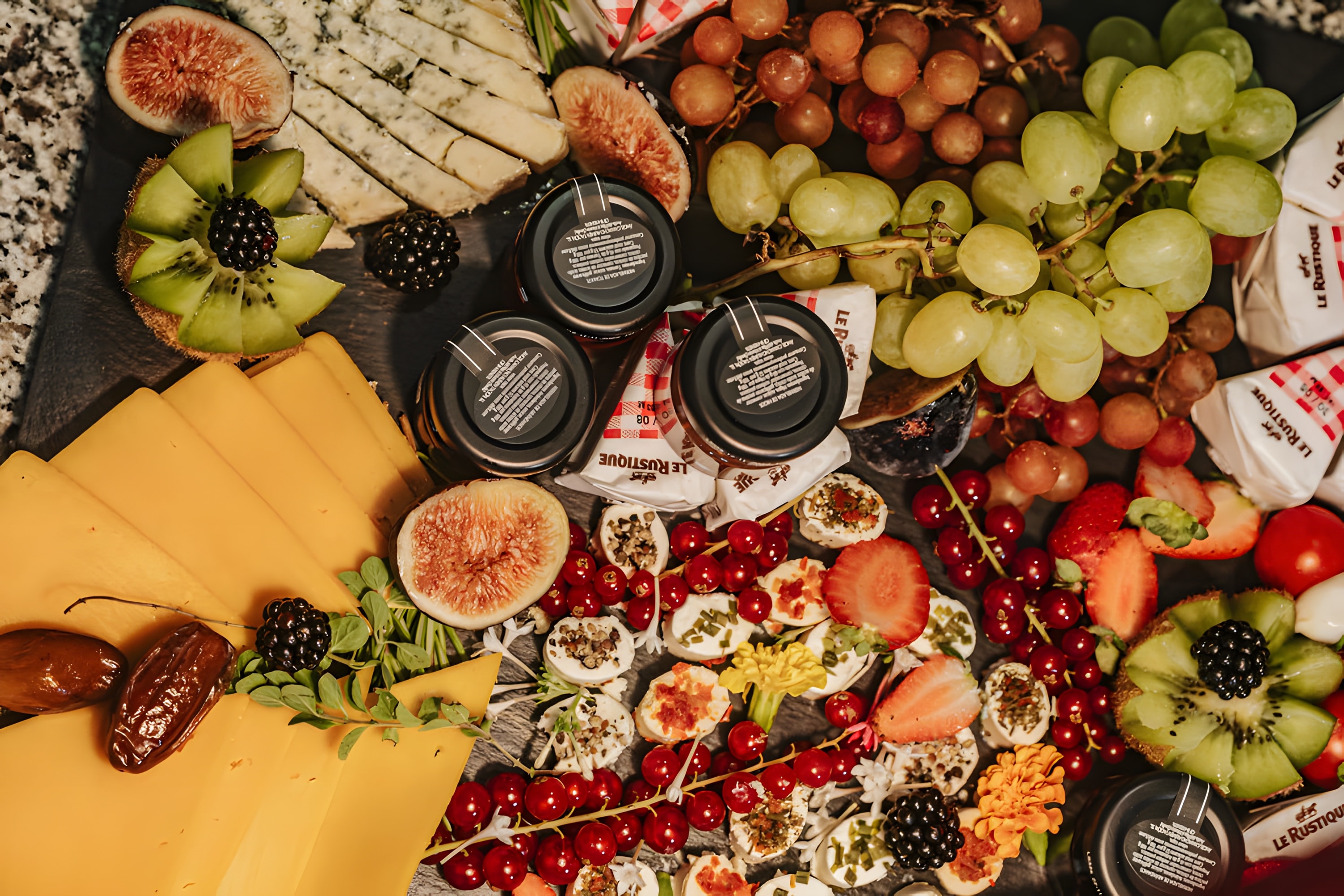Cheese, figs, grapes and red currants arranged on a grazing board