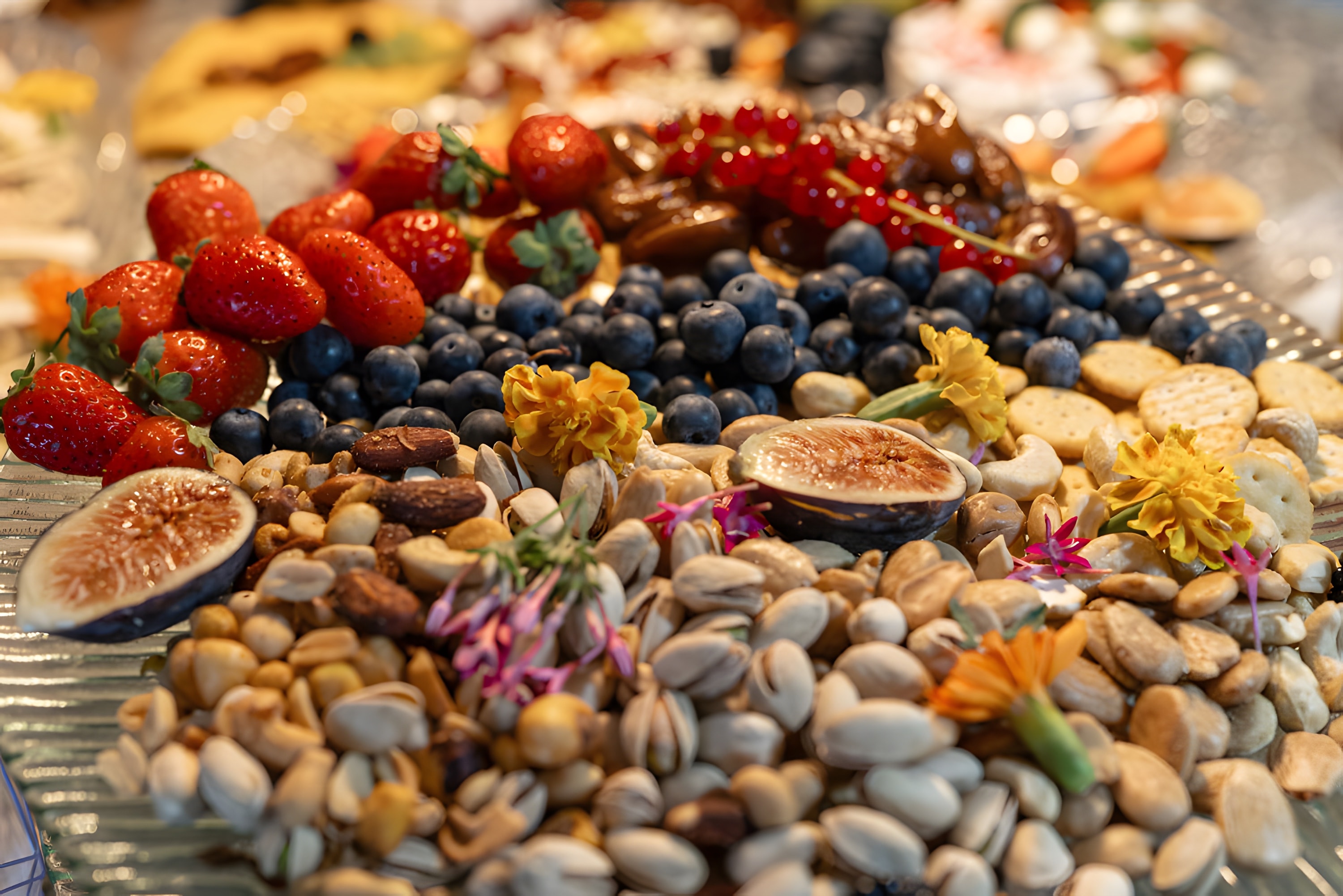 A close-up of strawberries, blueberries, figs, pistachios and edible flowers